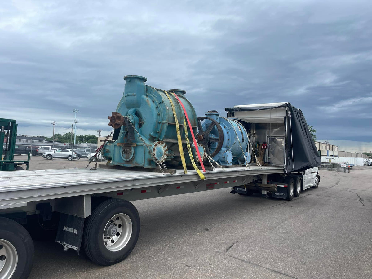 Surplus Nash vacuum pumps secured on a flatbed for pickup by DWP Industrial Sales